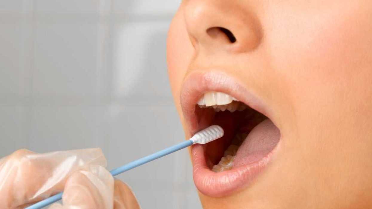 Person holding DNA swab in young woman's mouth