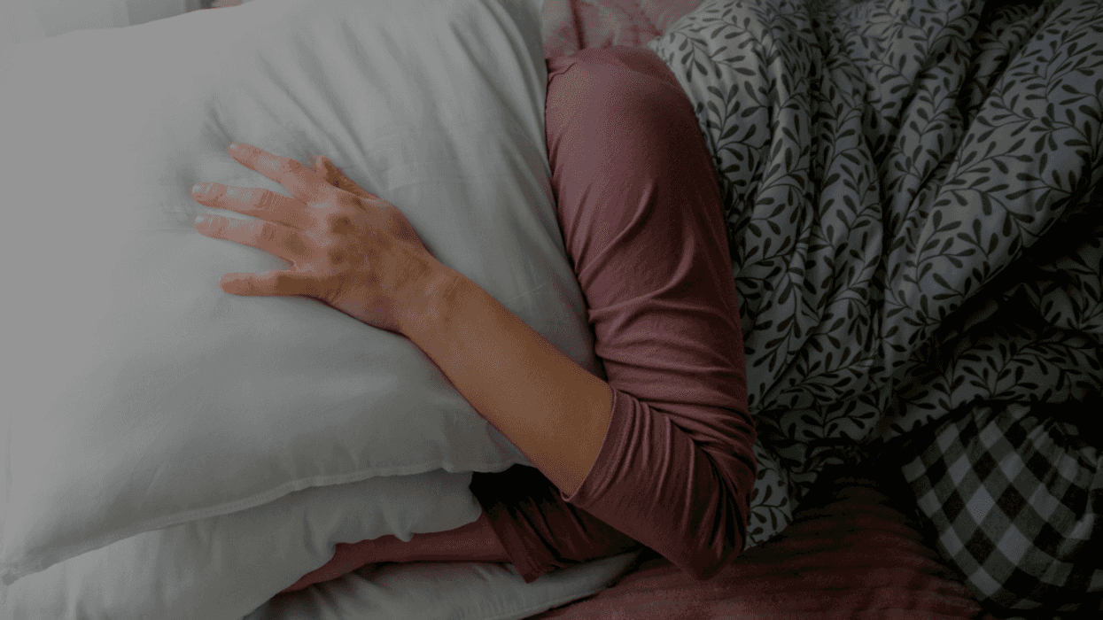 person in bed with pillow wrapped around head
