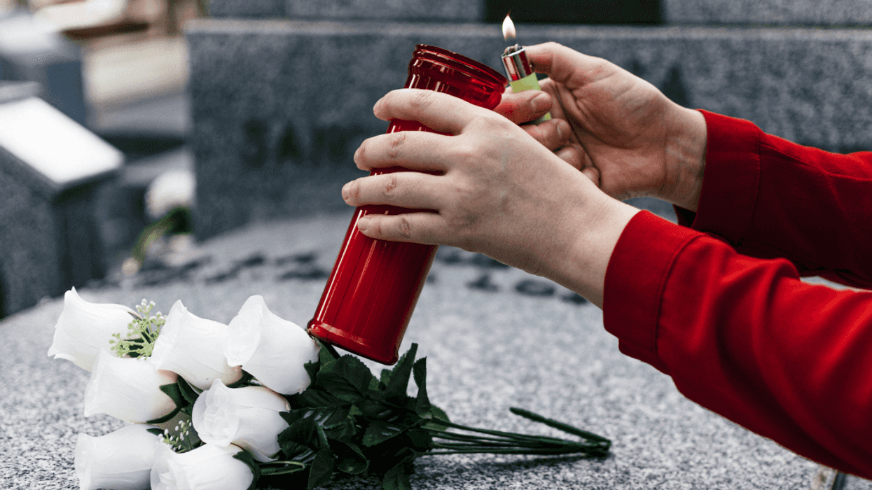 person lighting candle in cemetery