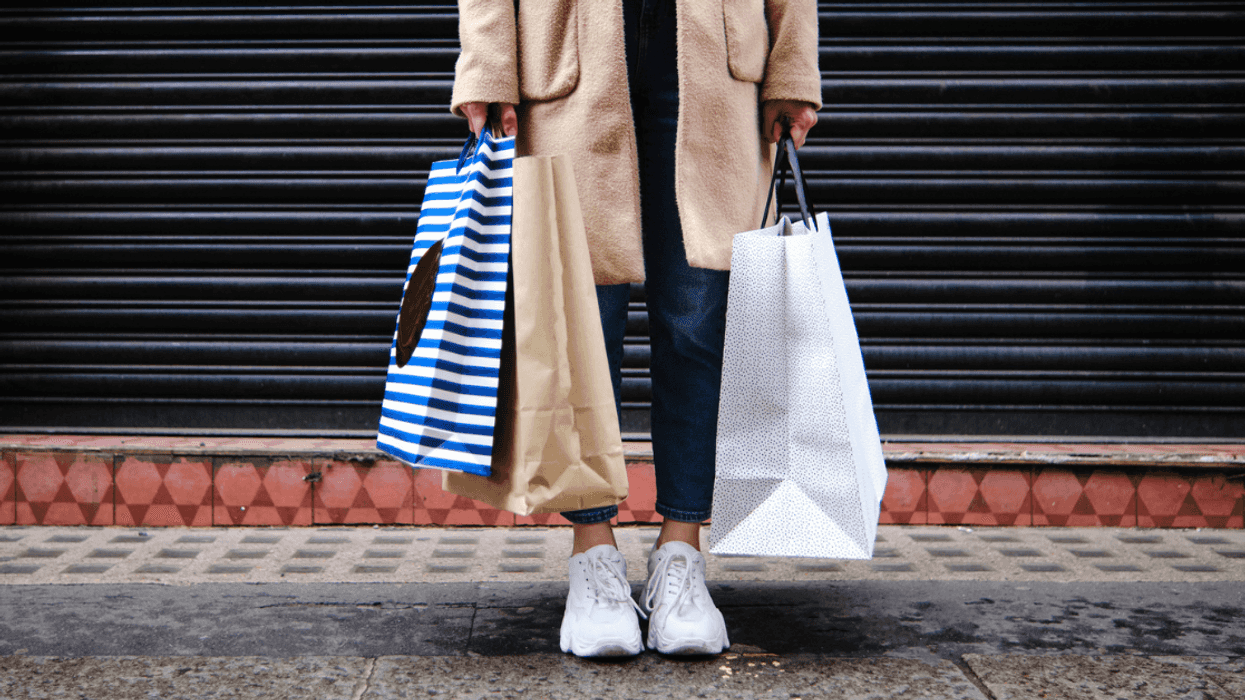 person on sidewalk holding shopping bags