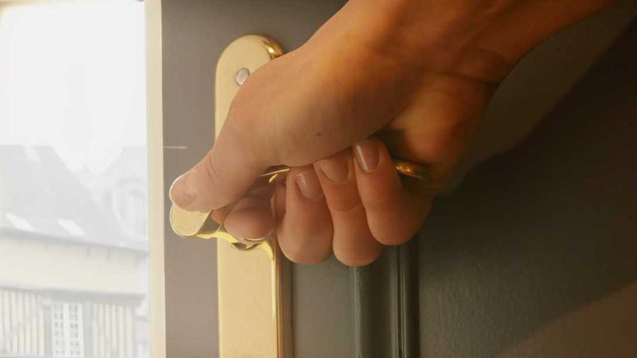 person opening front door of their home