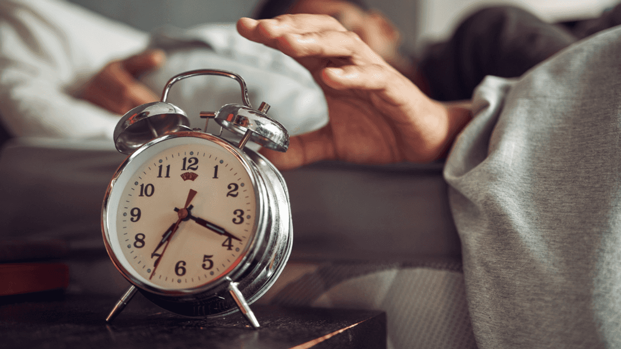 Person turning off an alarm clock