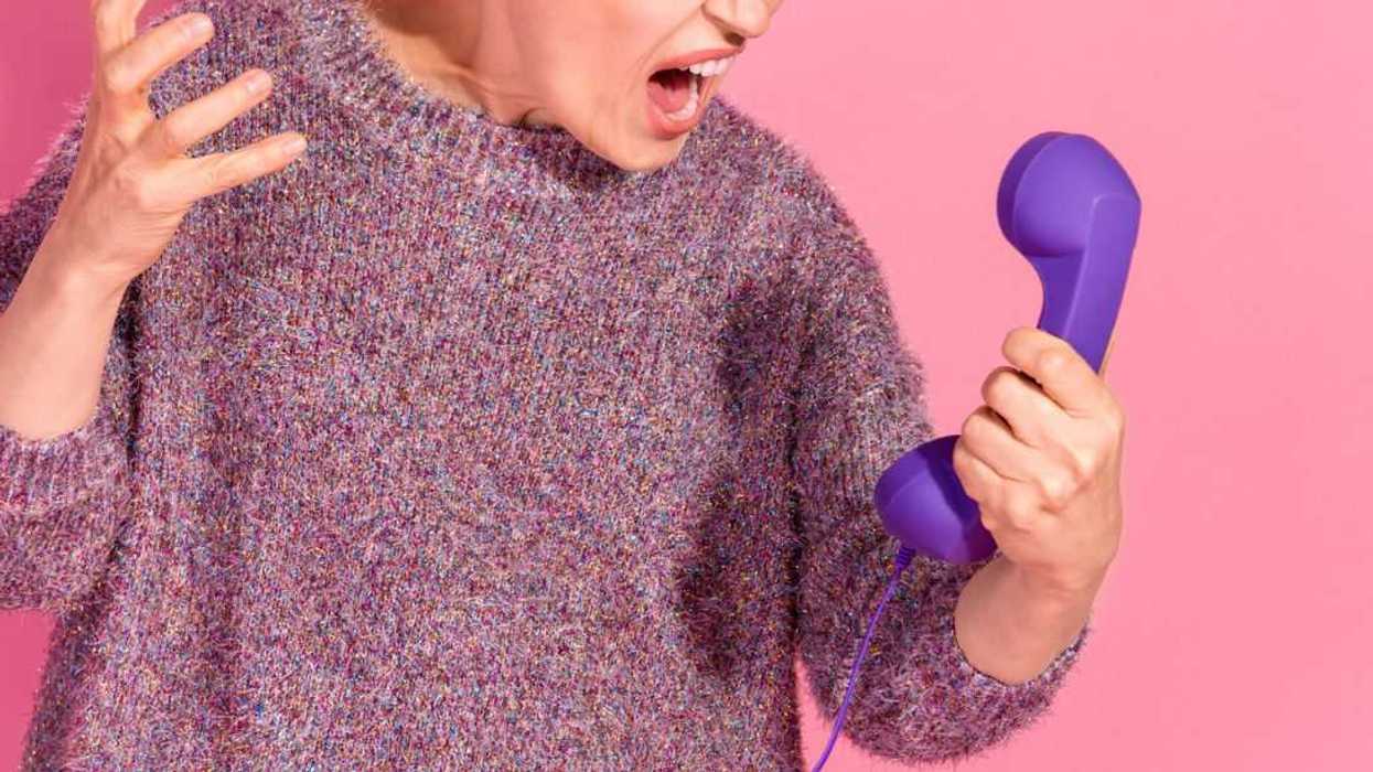 Photo of an arrogant, rude lady dressed in a pullover screaming into a retro phone, empty space isolated pink color background.