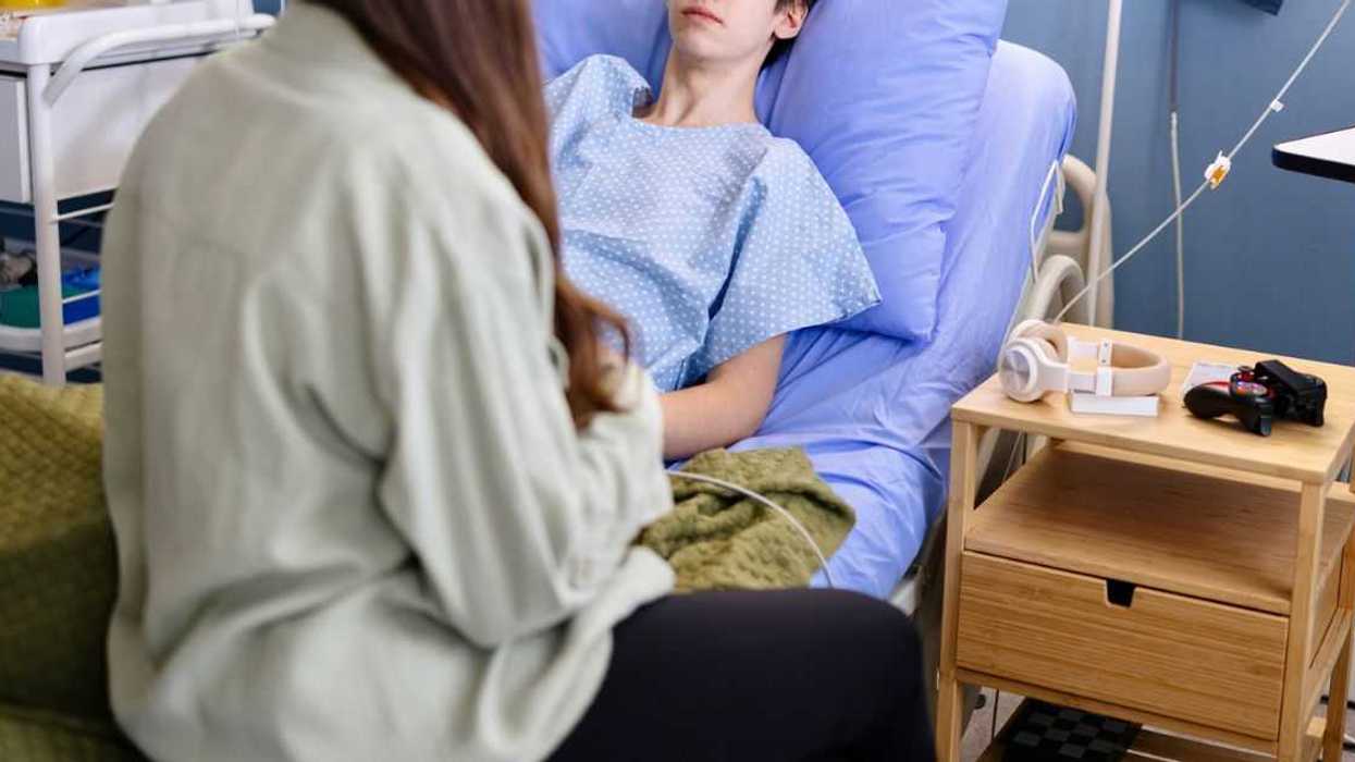 Portrait of a male teenager talking with his friend while lying in the hospital.