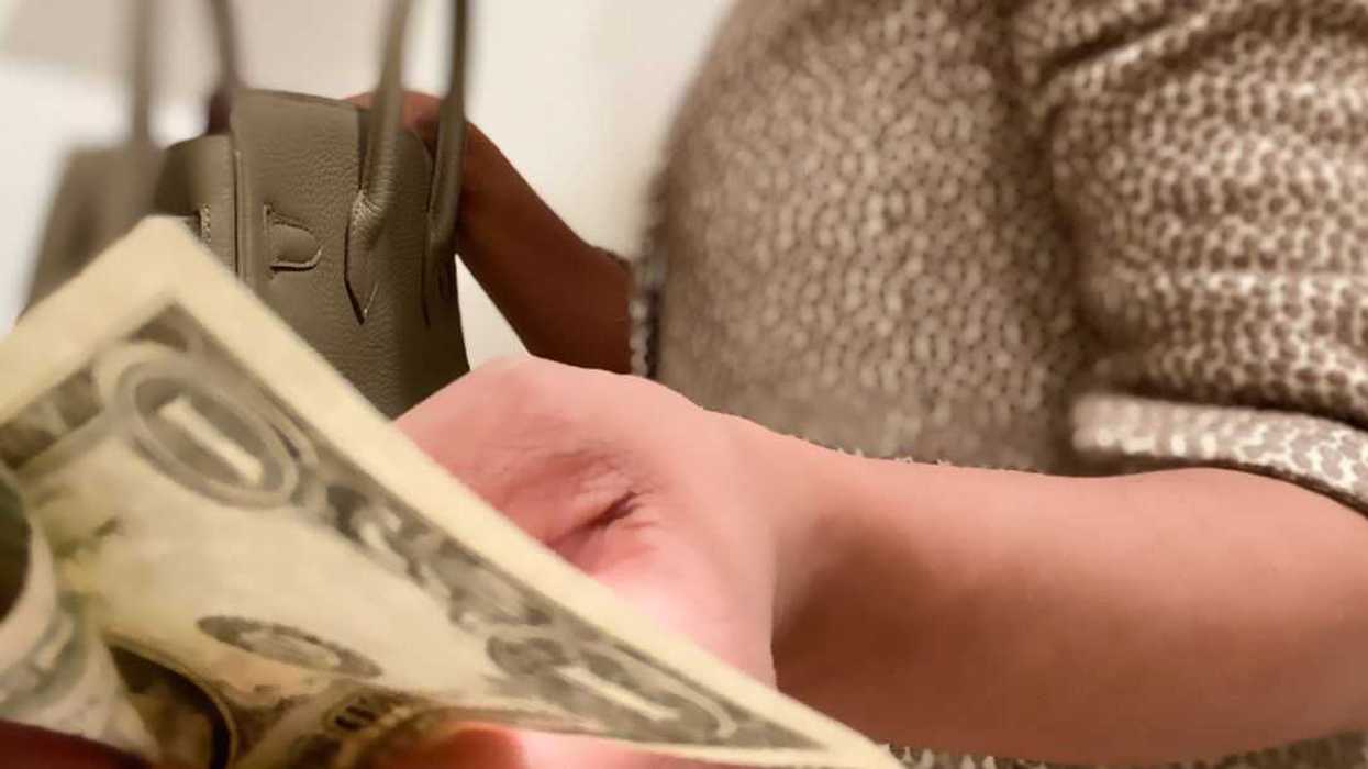Portrait of an unrecognizable professional woman wearing a suit and retrieving money from her purse.
