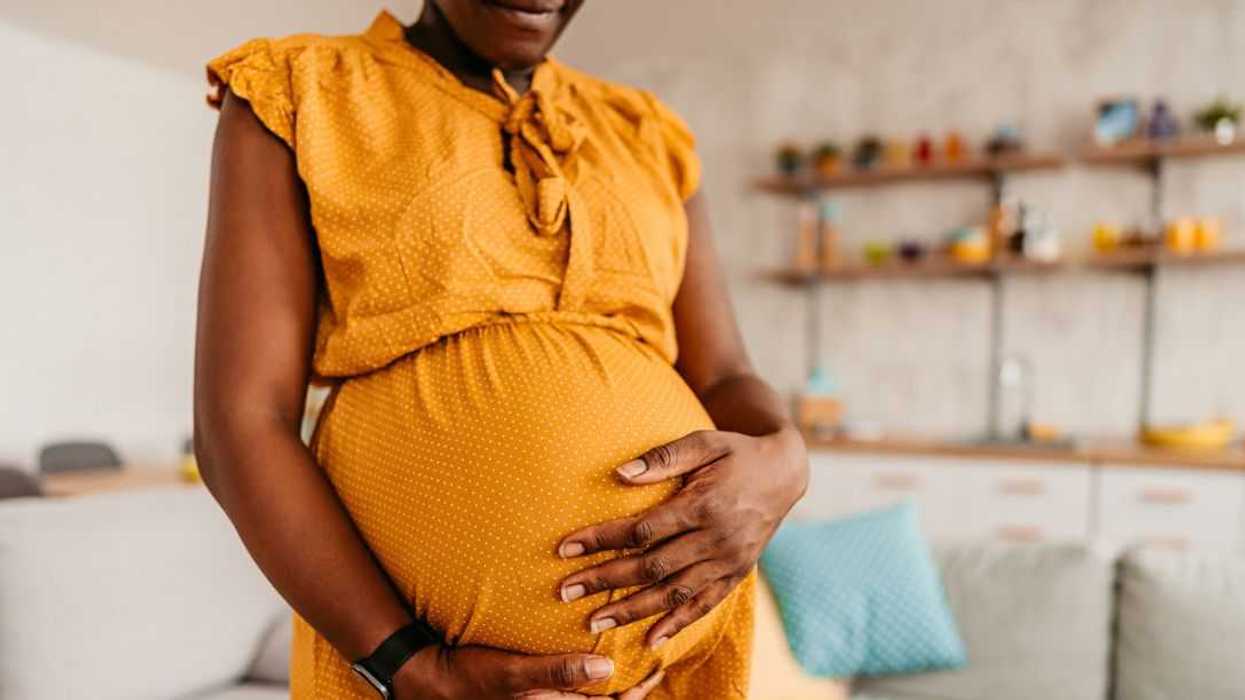 Portrait of beautiful pregnant mother holding her pregnant belly at home. Close-up.