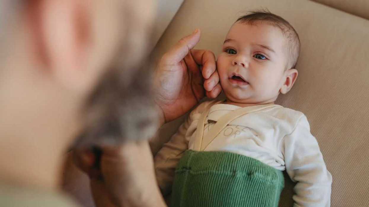 Portrait of cute calm baby lying on sofa, father caressing his soft cheek