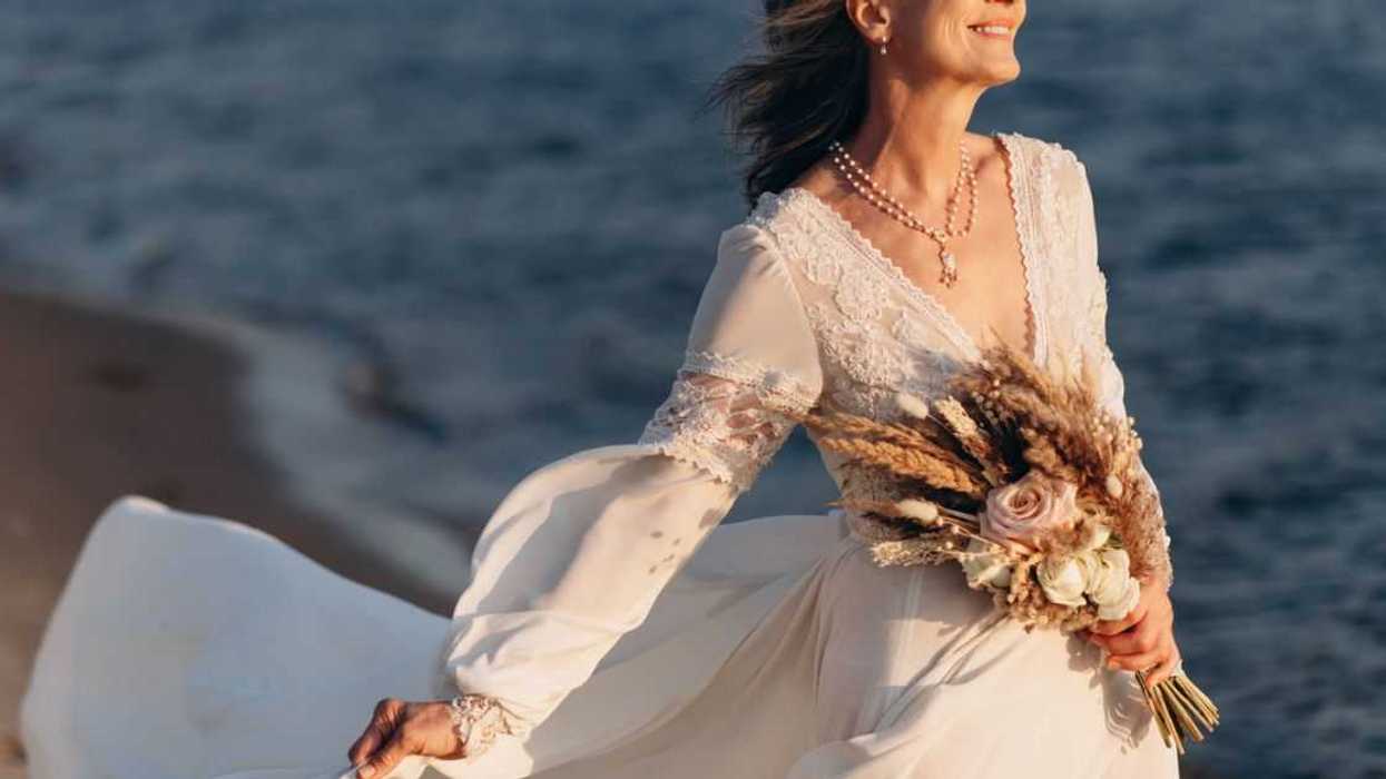 Portrait of senior bride with bouquet on seashore.