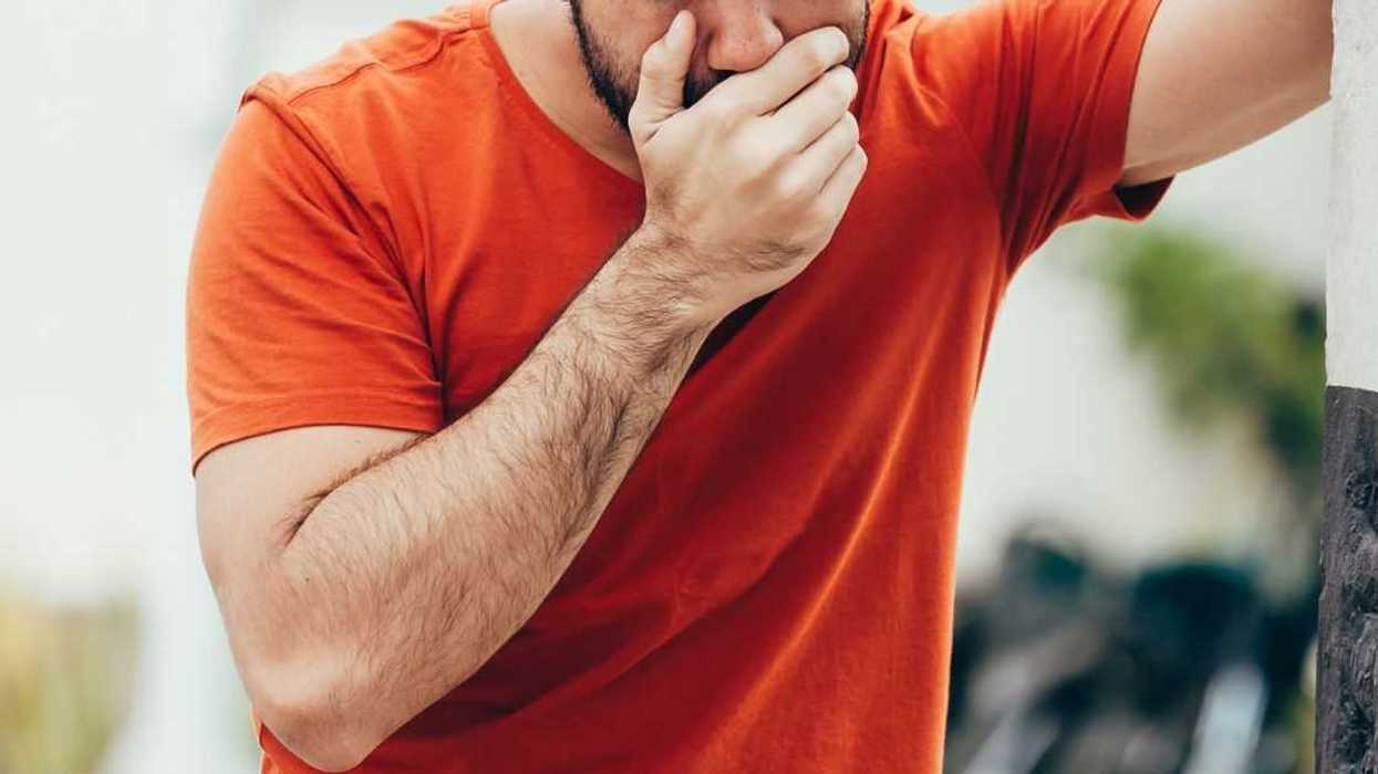 Portrait of young man drunk or sick vomiting outdoors
