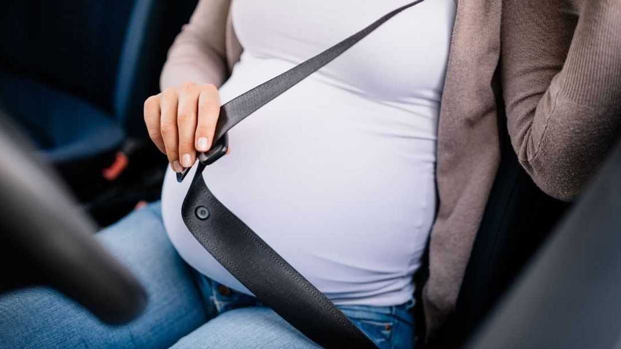 pregnant woman buckling up in driver's seat