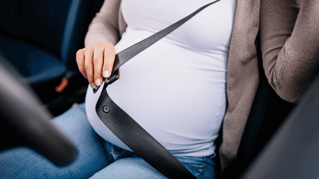 pregnant woman buckling up in driver's seat