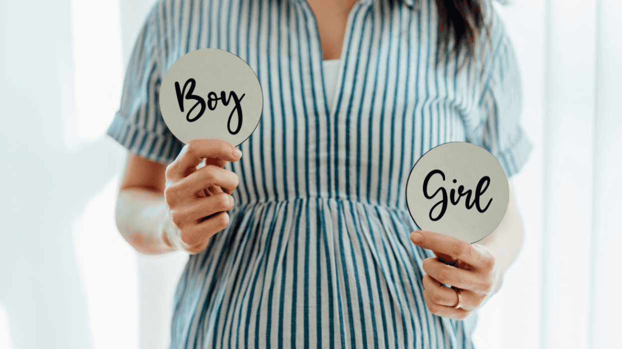 pregnant woman holding paddle signs saying boy and girl
