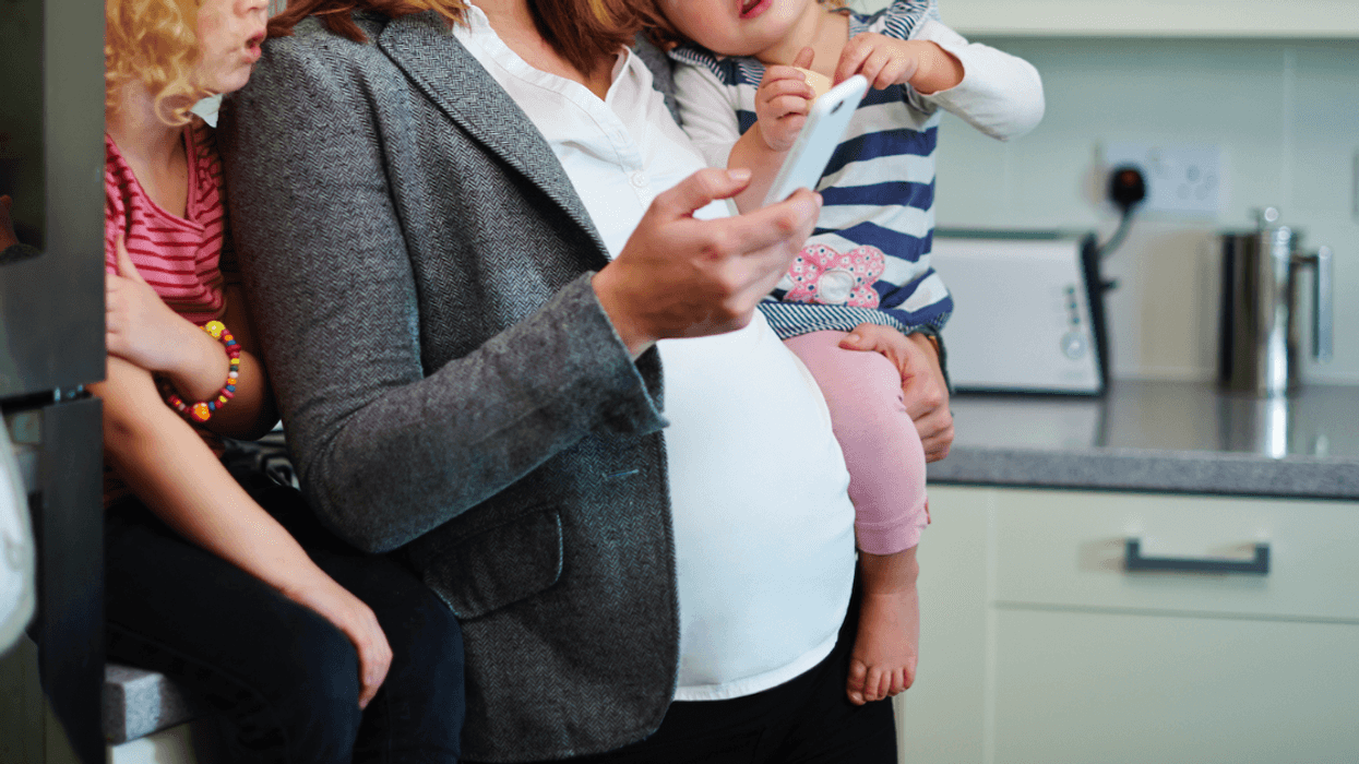 Pregnant woman holding two children.