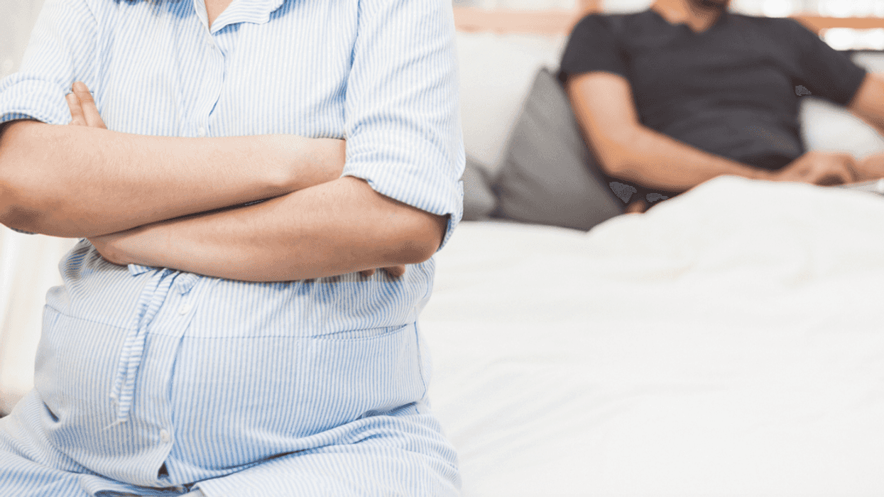 Pregnant woman on bed with husband.