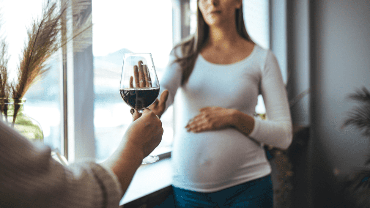 pregnant woman refusing a glass of wine
