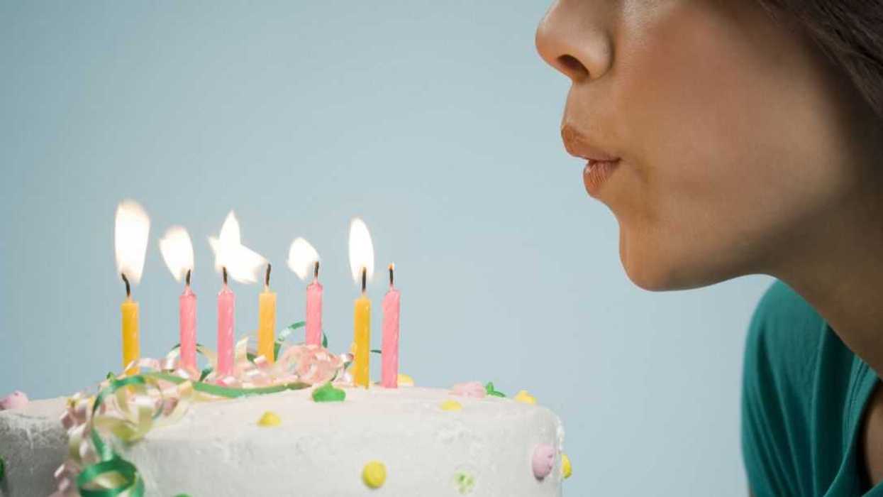 Profile of a woman blowing out candles on a birthday cake .