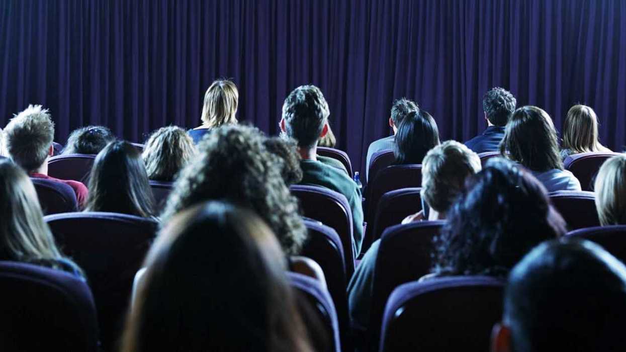 Rear view crowd of people in a movie theater.