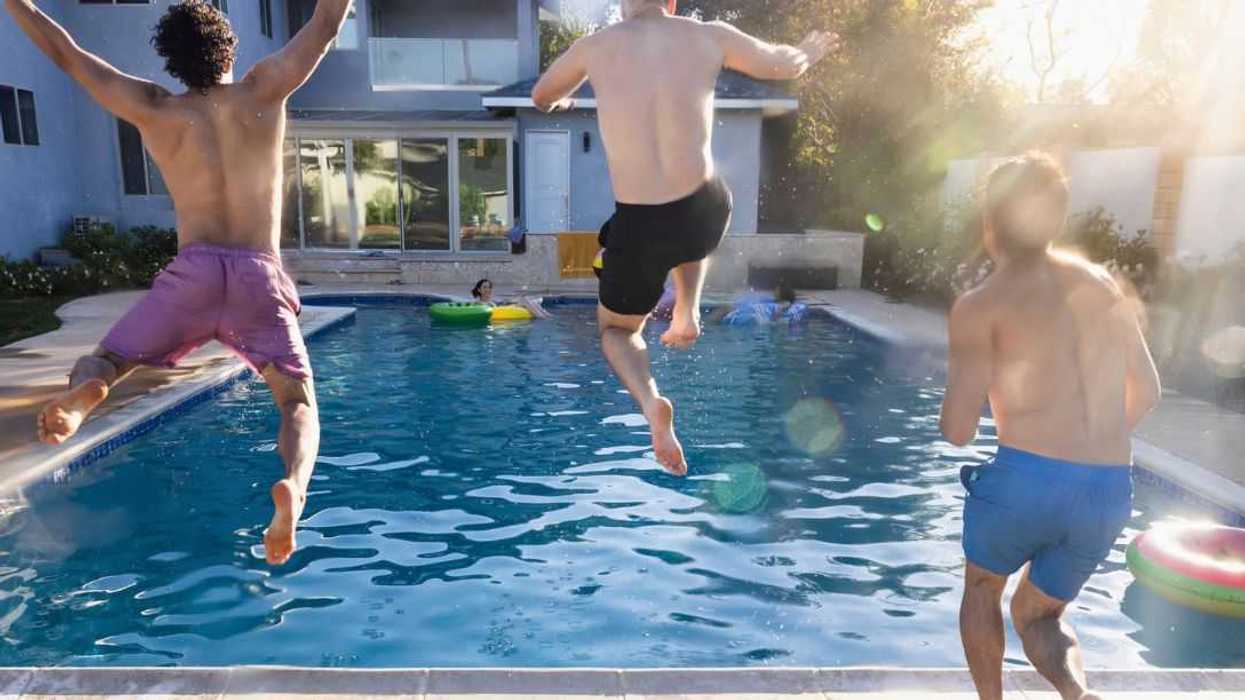 Rear view of male friends jumping into swimming pool together.