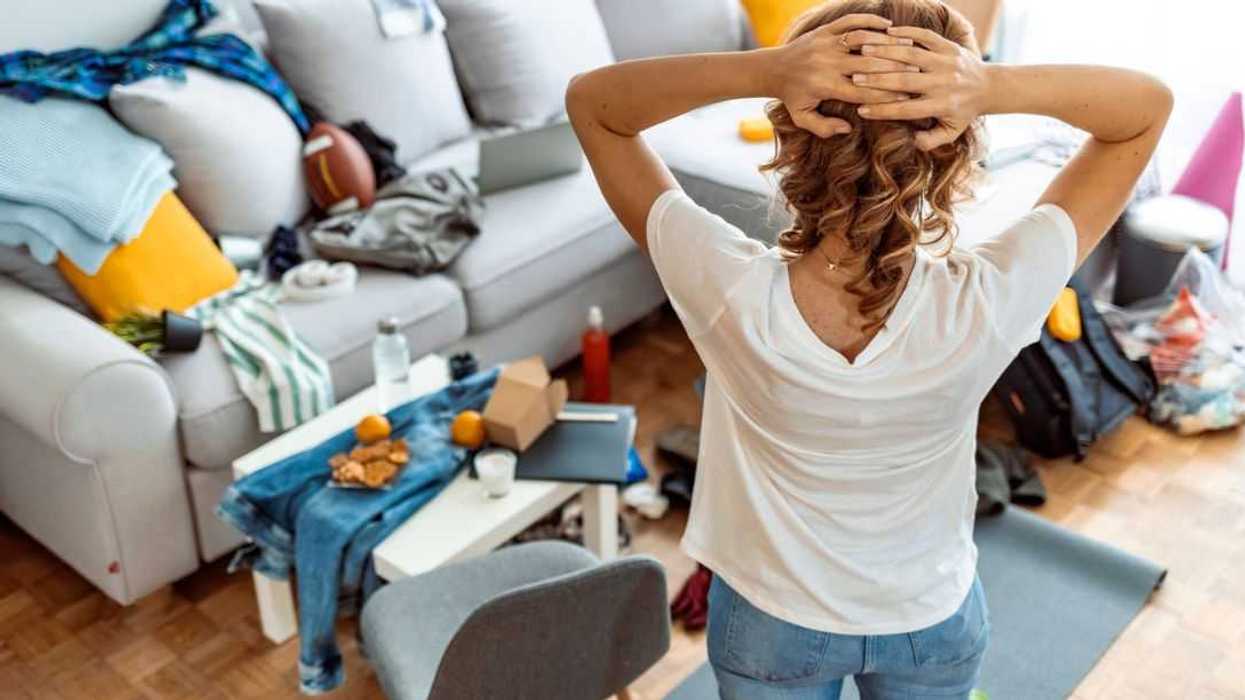 Rear view of Mature housewife standing while preparing for cleaning at home.