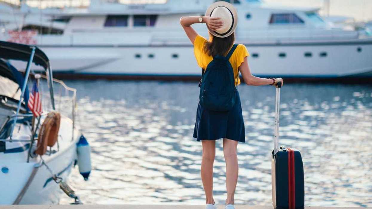 Rear view of tourist woman staring at the yachts before boarding.