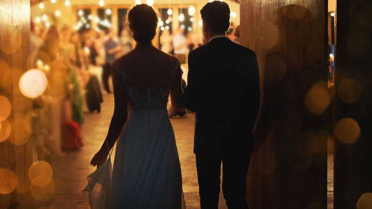 Rearview shot of a young couple arriving hand in hand at their wedding reception