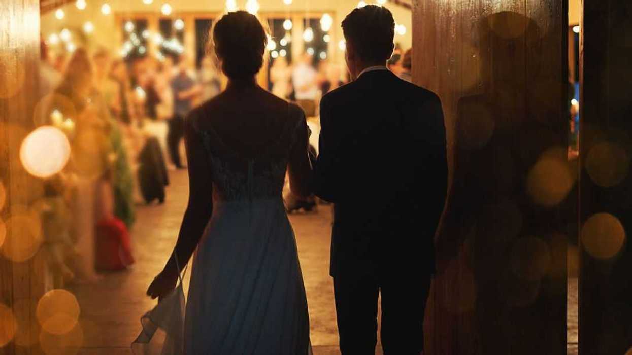 Rearview shot of a young couple arriving hand in hand at their wedding reception.