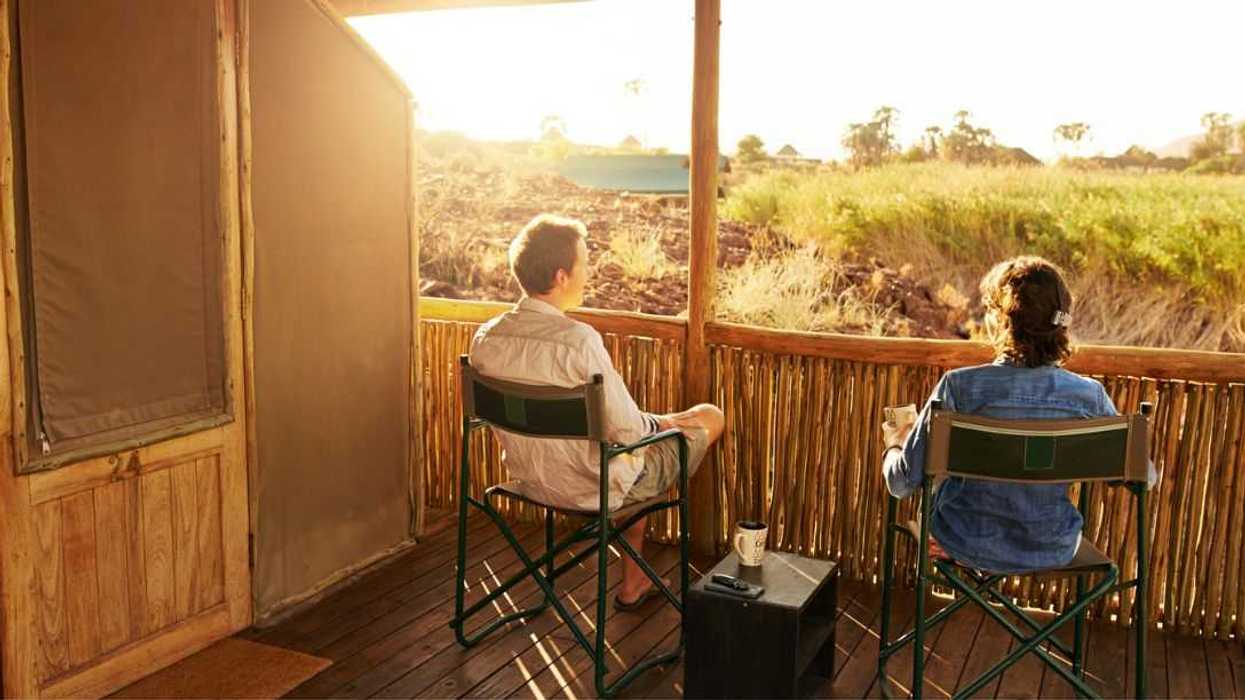 Rearview shot of an unrecognizable couple looking at the view while sitting on their suite's veranda at a resort in nature.