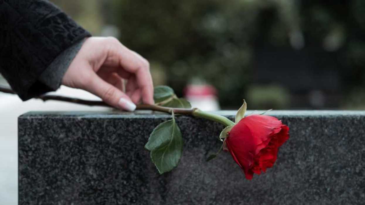 Red rose being placed on tombstone