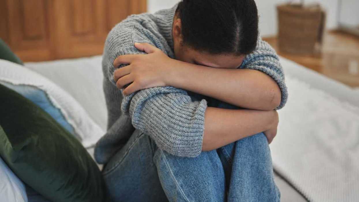 Sad depressed adolescent teen girl crying at home, worried teenager hugging knees suffering from depression.