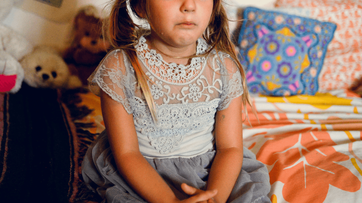 Sad little girl crying alone in her bedroom