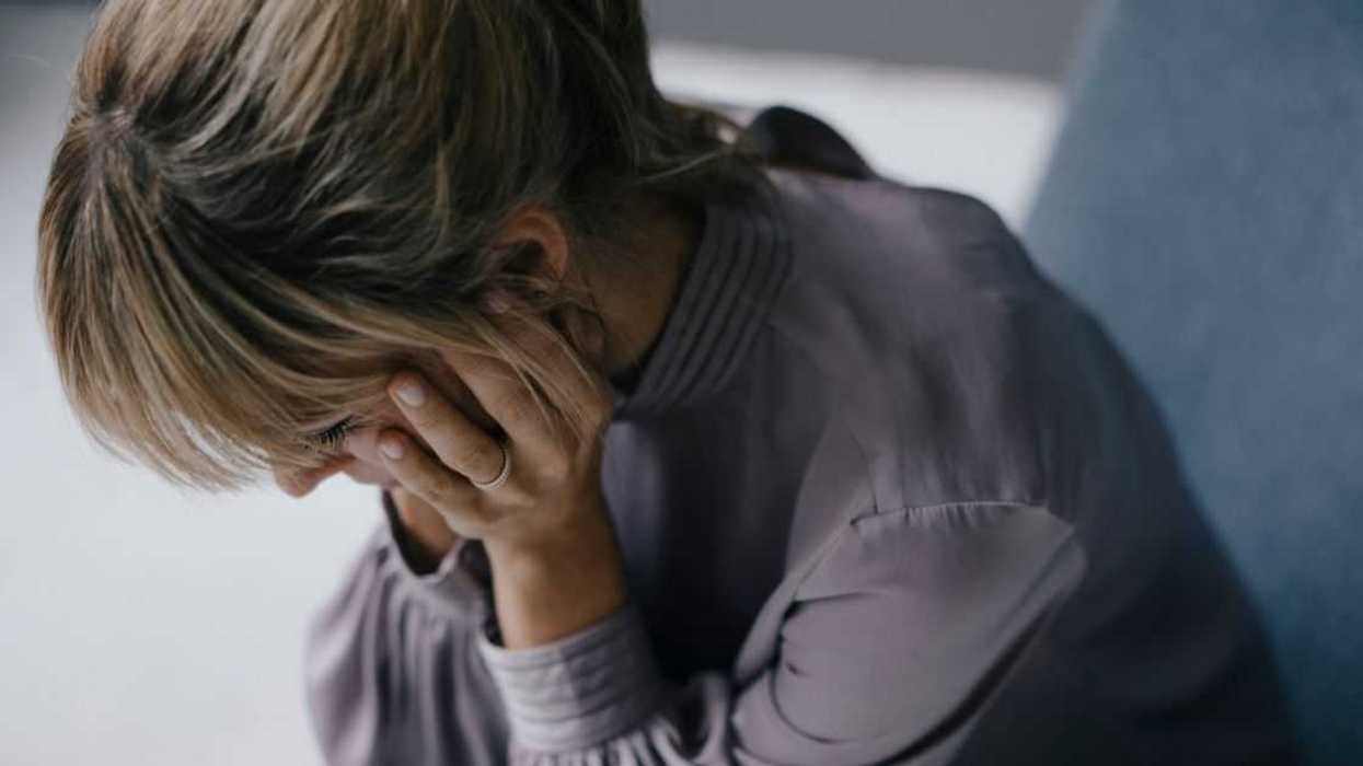 Sad woman sitting in armchair with head in hands