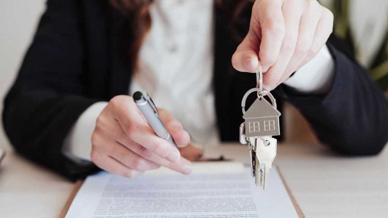 Saleswoman holding house keys and pen at office.