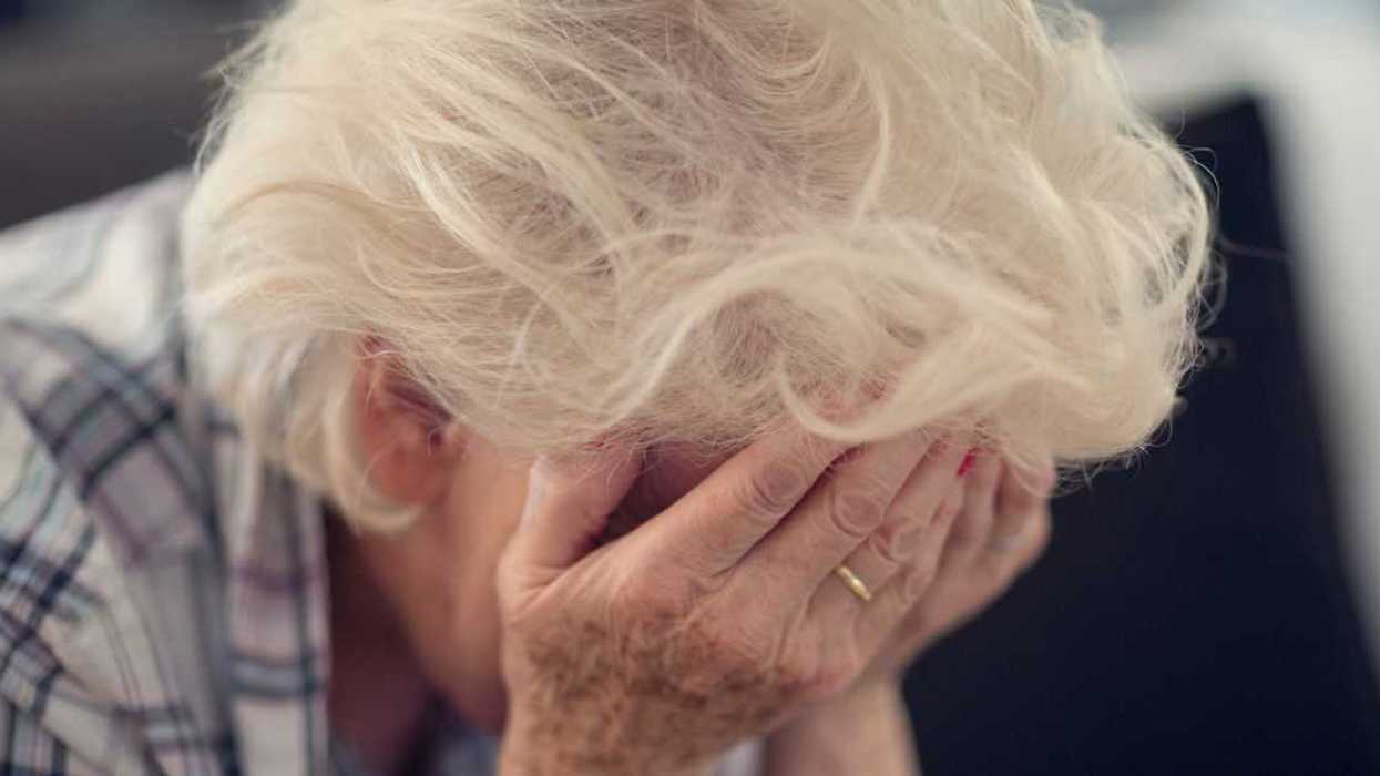 Senior woman holding her head in her hands in despair.