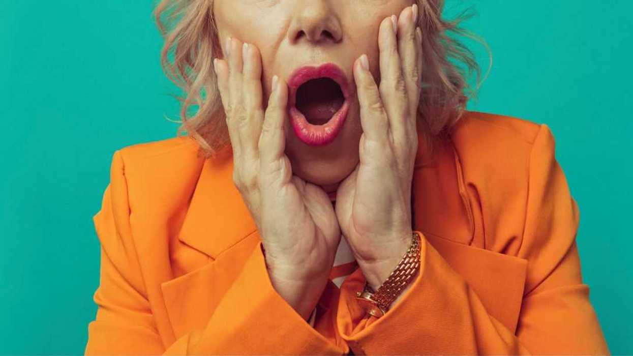 Shocked senior woman against turquoise background.