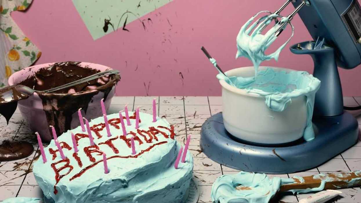 Shot of a cake saying "Happy Birthday." It sits among a messy counter with baking ingredients.