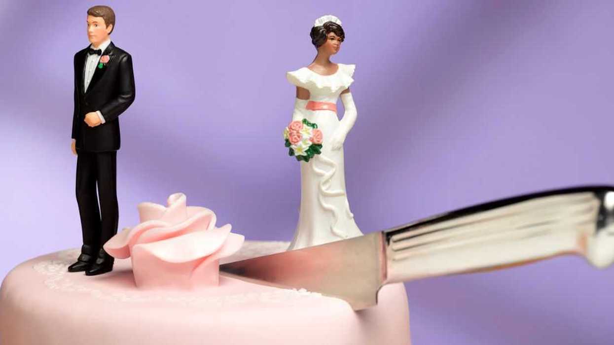 Shot of a cake topper couple, the couple is separated on top of the wedding cake by a knife cutting between them.