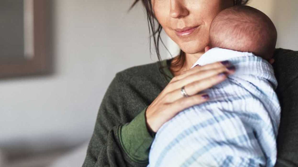 Shot of a cheerful young woman holding her little infant son at home during the day.