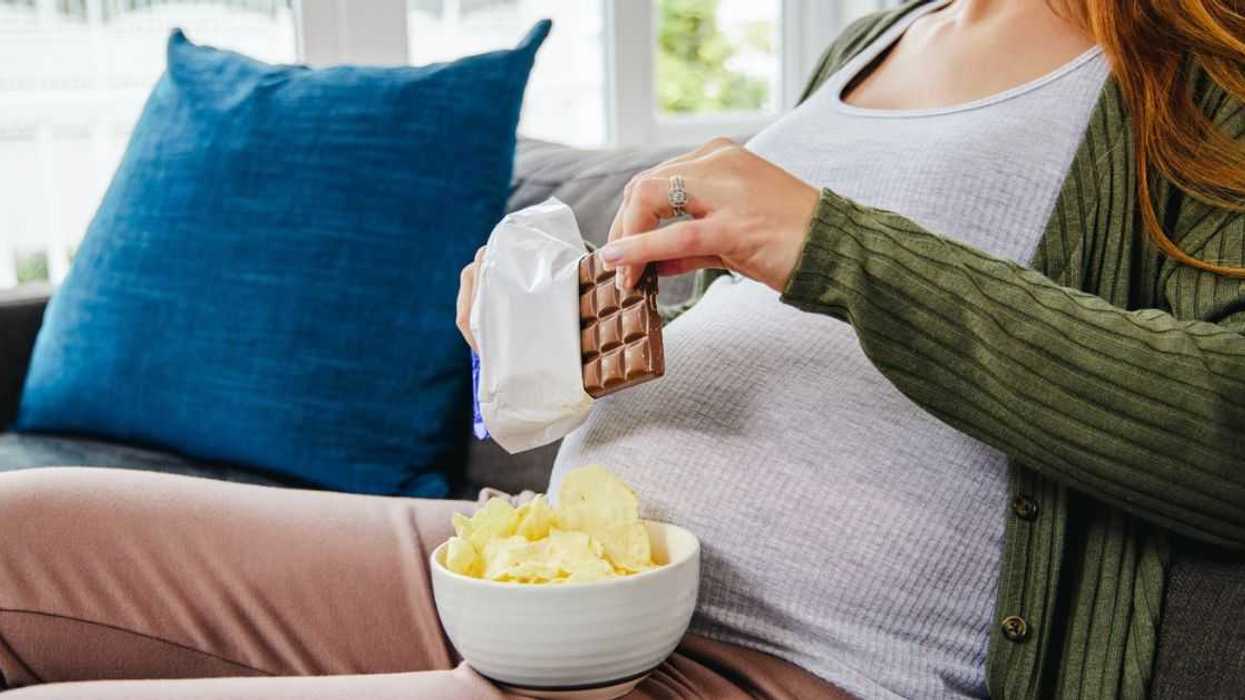 Shot of an expecting mother enjoying some snacks during the day