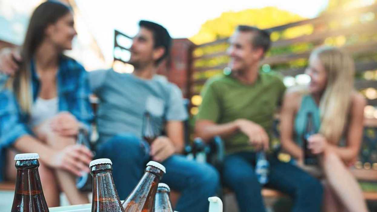 Shot of bottled beers chilling in a cooler box with a group of friends hanging out in the background.
