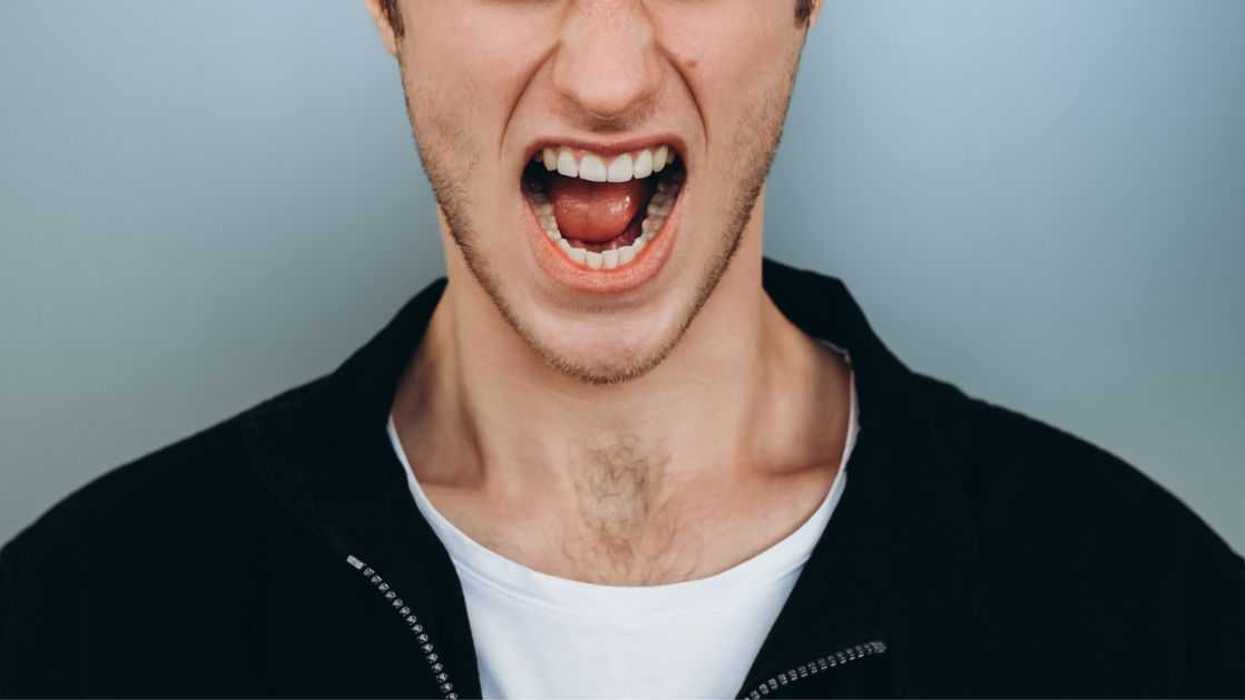 Shouting young man against a blue-gray backdrop.
