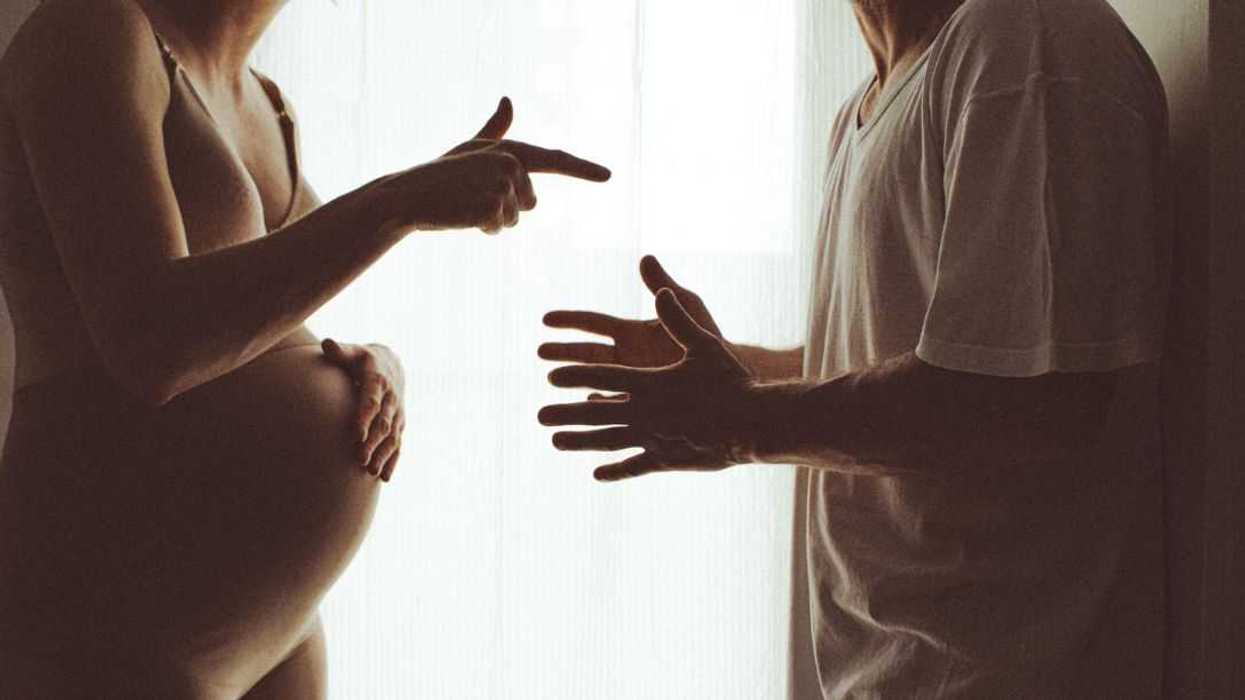 Silhouette of a pregnant woman and a man arguing..Close-up of their hands.