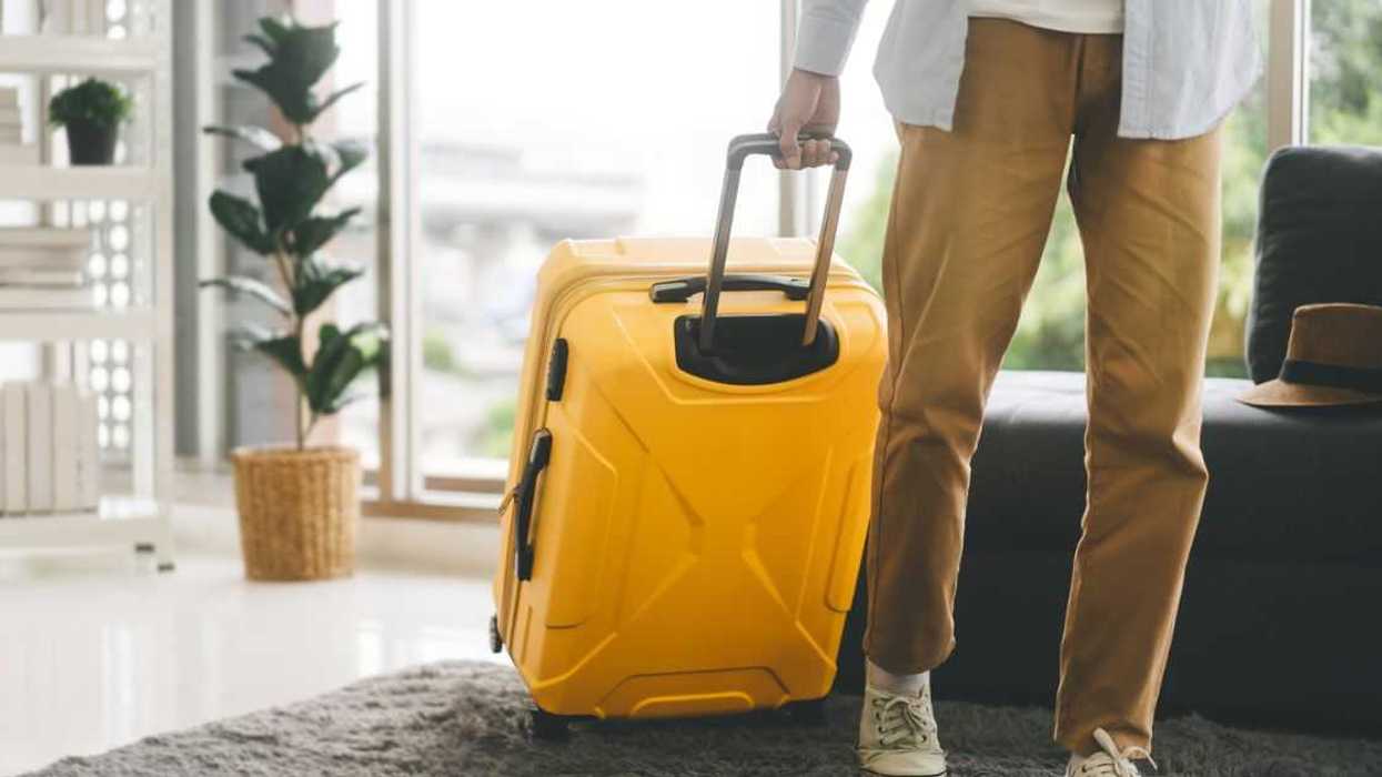 Single man pulling a yellow suitcase, leaving a hotel room.