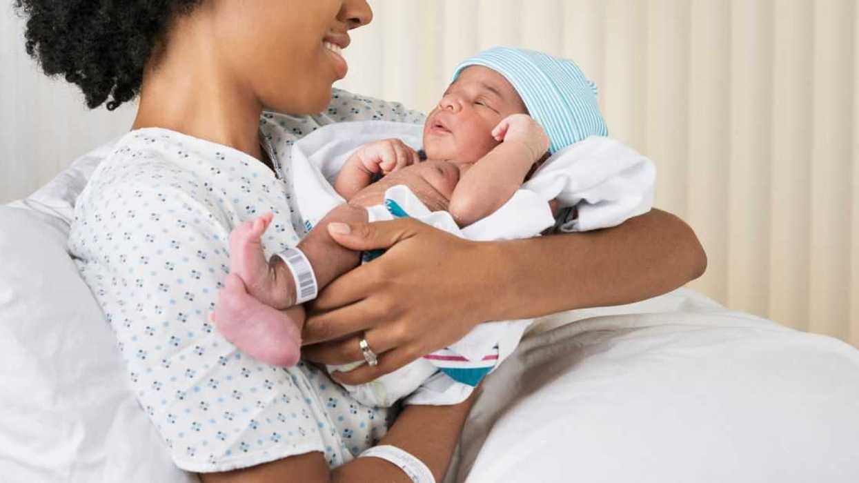 Smiling mother holding newborn baby in hospital.