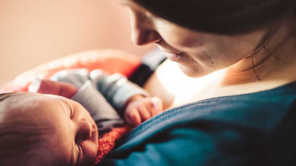 Smiling mother looking at her newborn baby daughter.