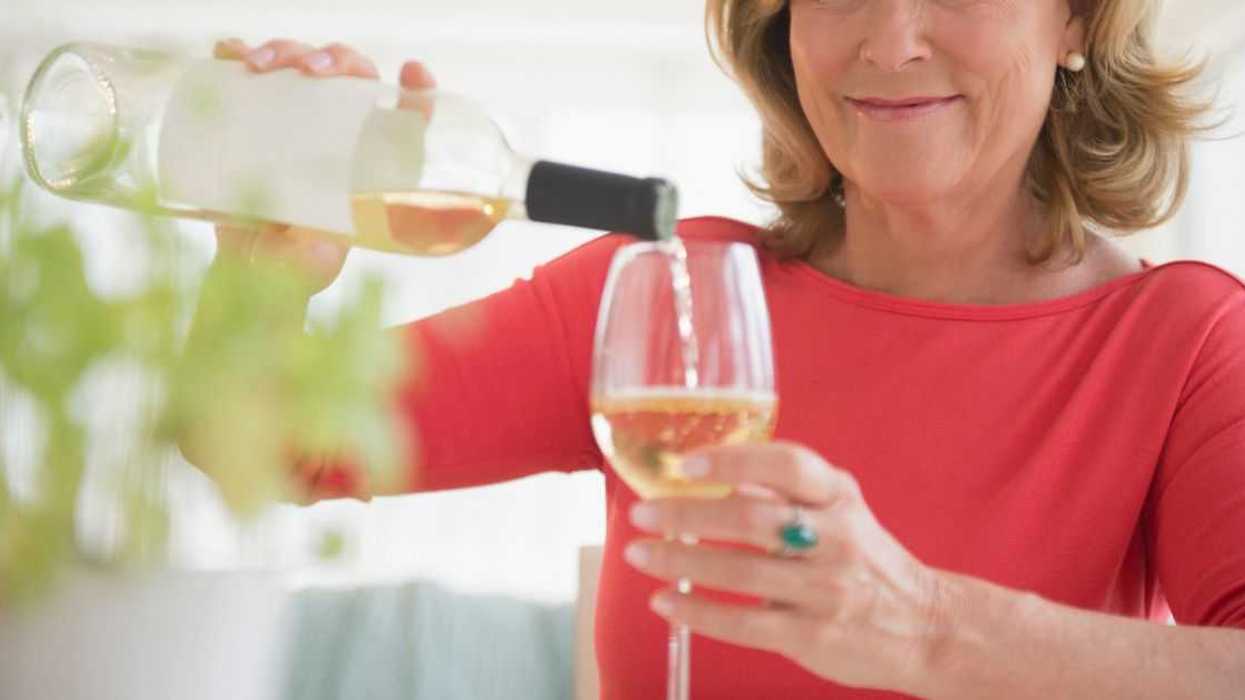 Smiling woman pouring glass of white wine.