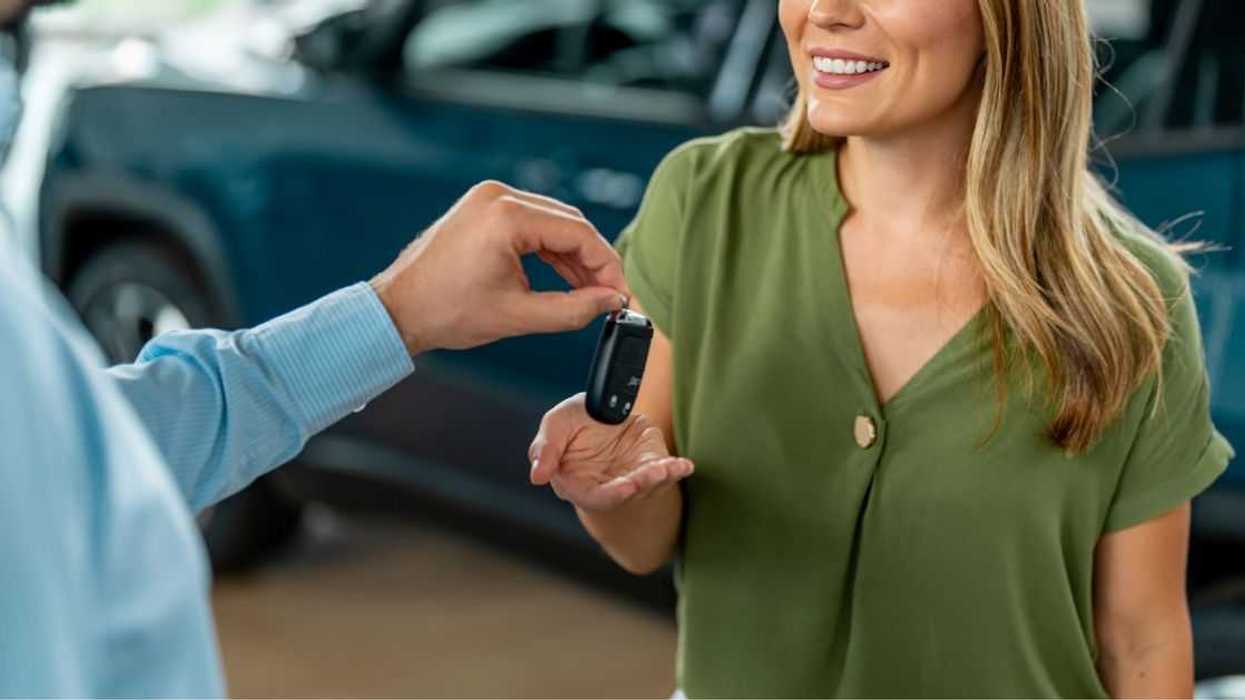 Smiling woman receiving her car keys in an auto saloon.