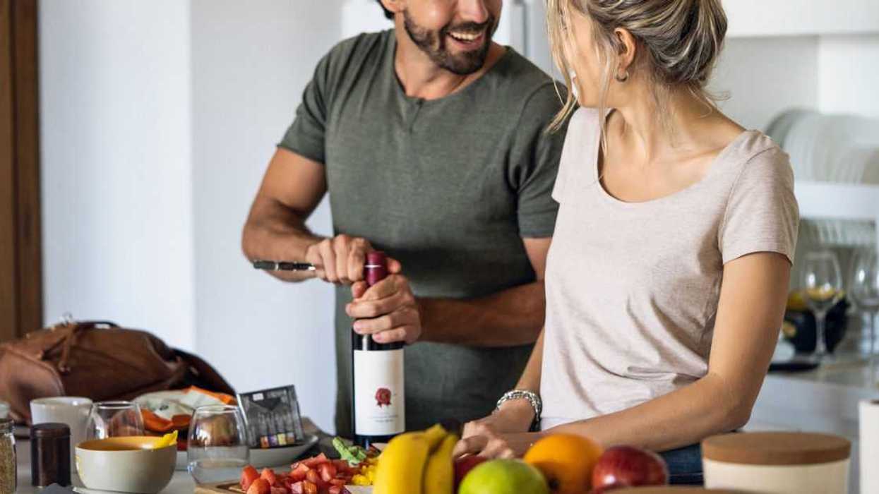 Smiling young couple preparing food in kitchen at home.