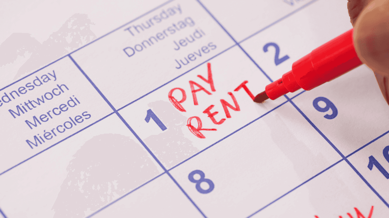 Someone writing "pay rent" in red on a calendar.