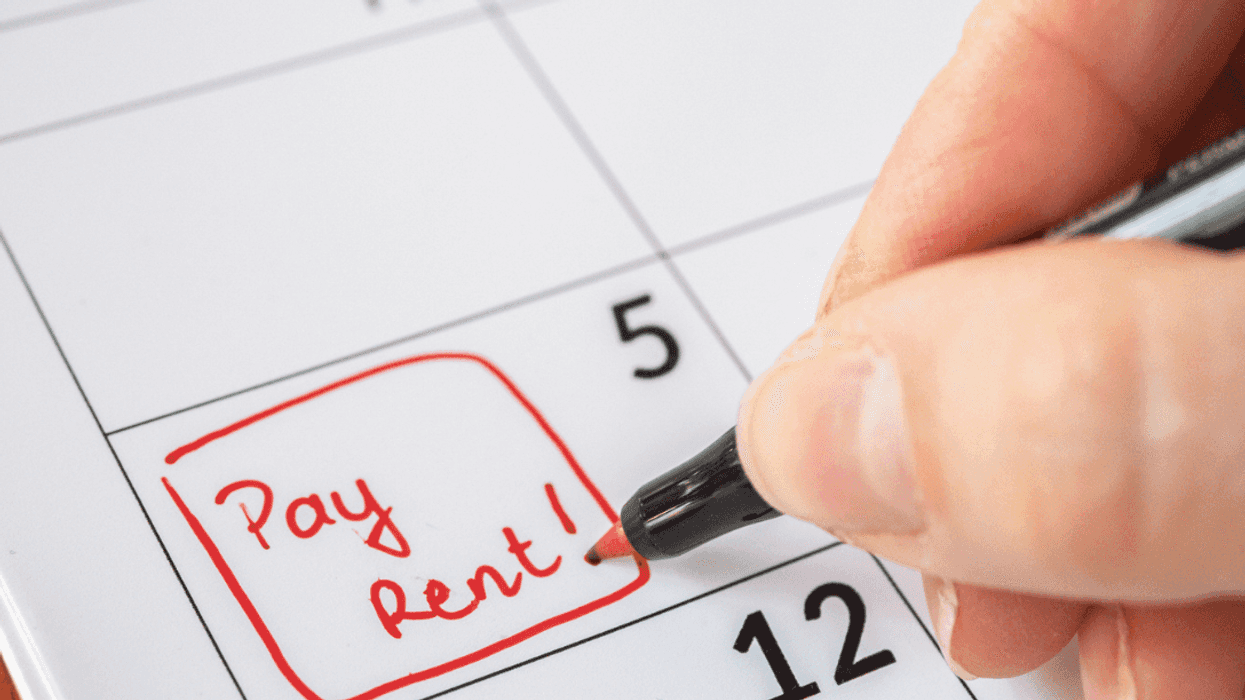 Someone writing "pay rent" on a calendar.