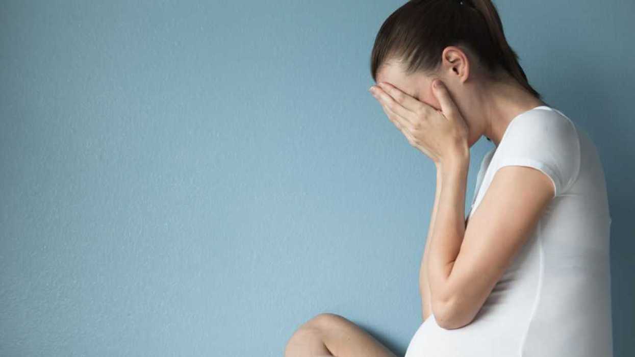 Stressed pregnant woman against blue background.